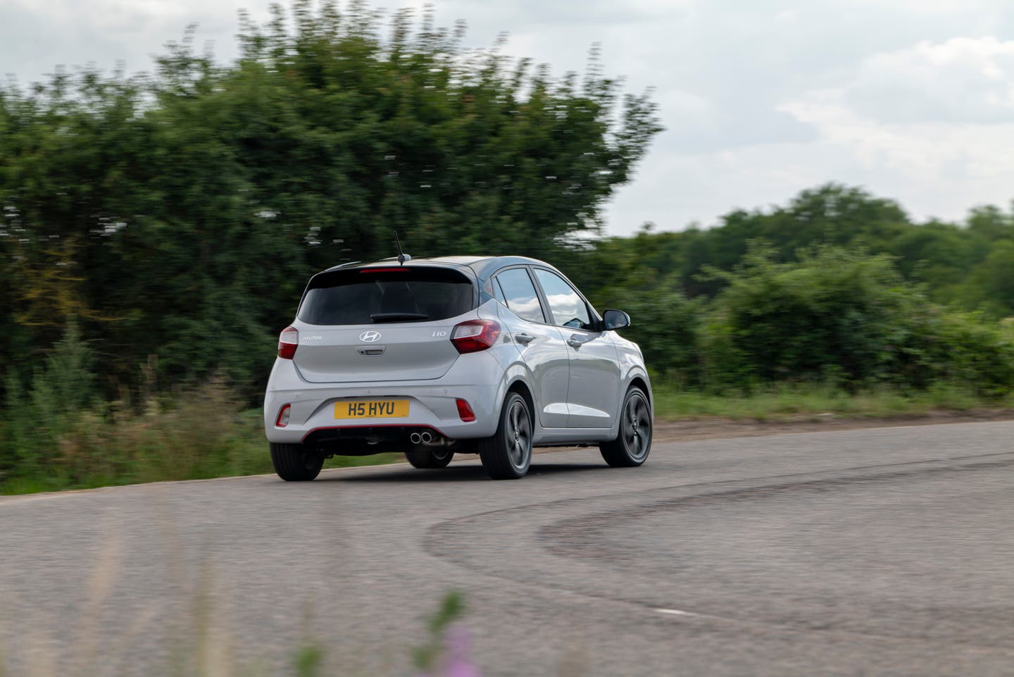 White Hyundai i10 N Line driving along a road, shot from the rear