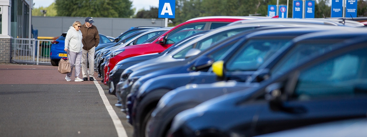 A pair of car shoppers browse a row of cars