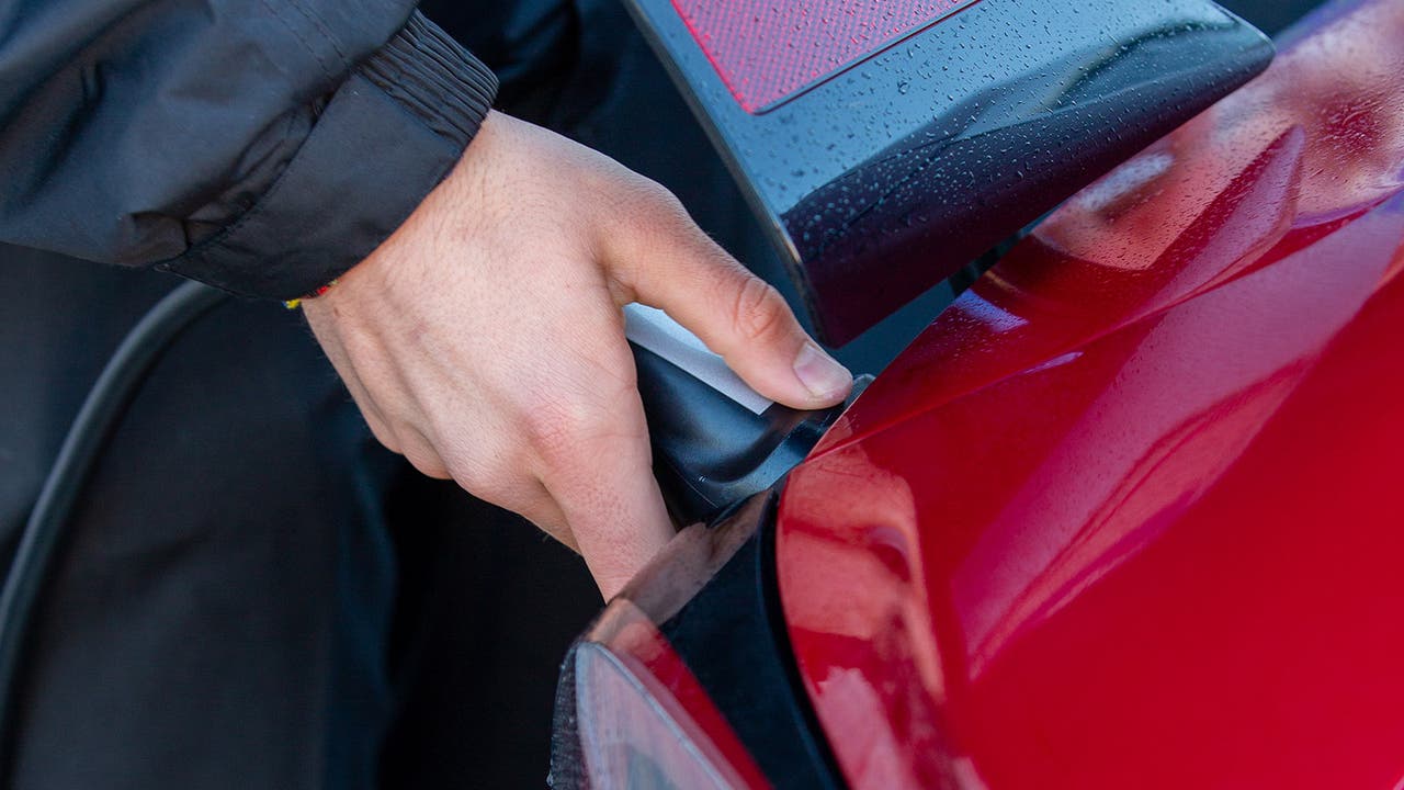 Charging plug being connected to a red Tesla Model 3