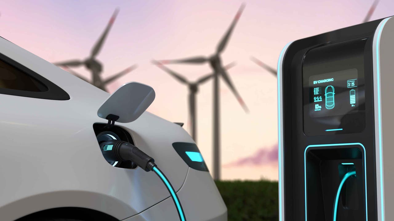 Stock photo of electric car next to wind turbines