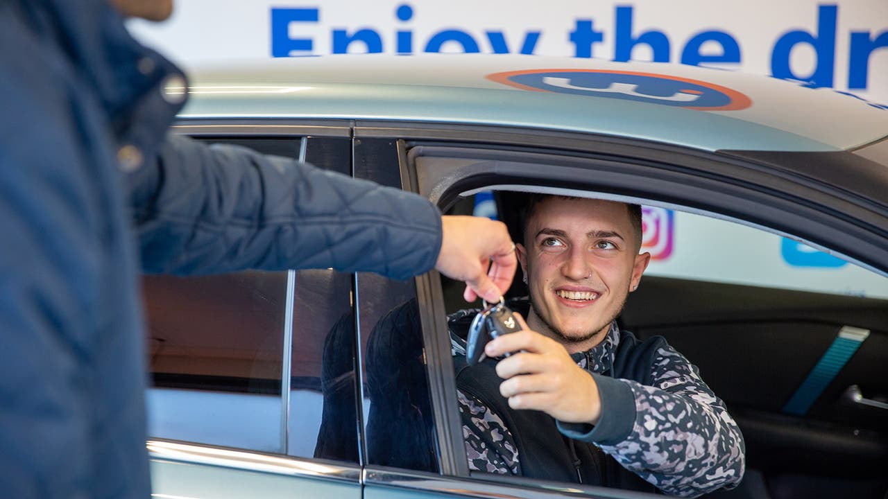 Young man being handed keys to a test car