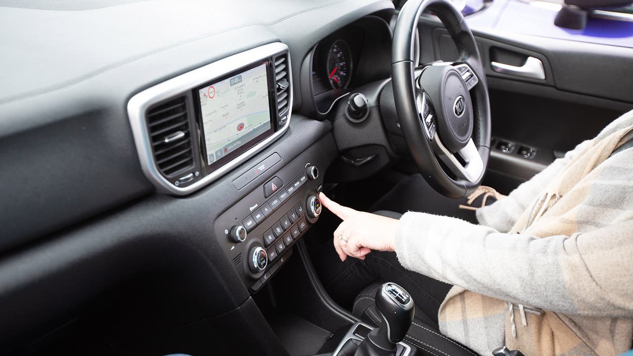 Motorpoint customer sat in a car pressing a button on the dashboard