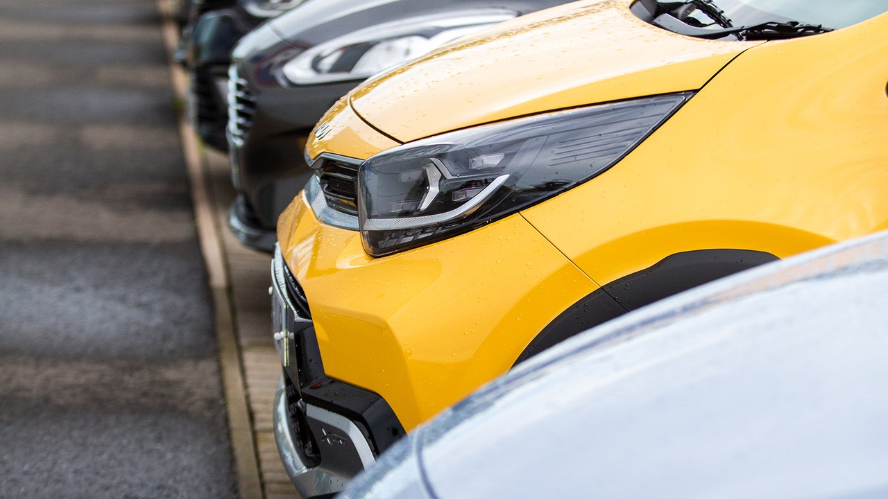 Closeup of the front of a bight yellow Kia Picanto parked at a Motorpoint store