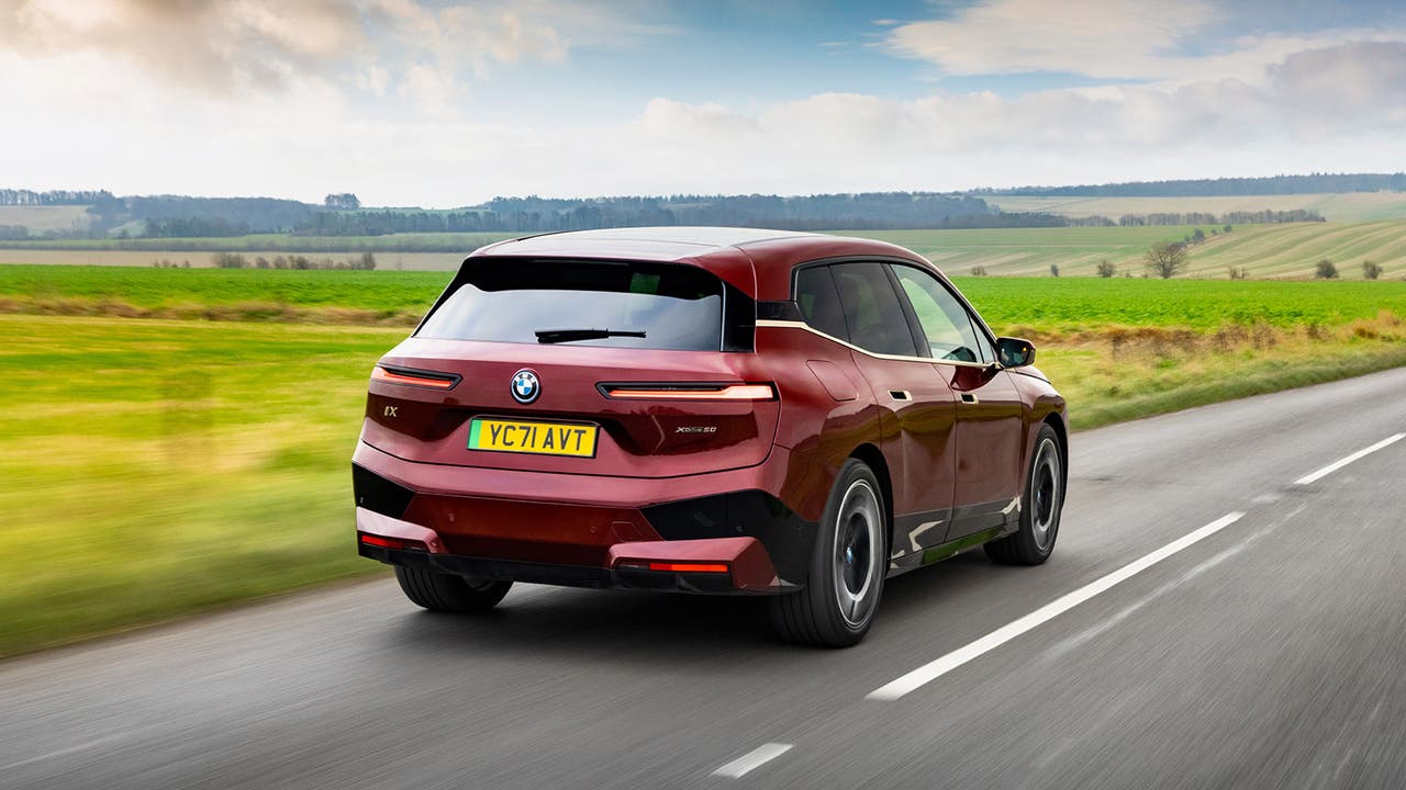 BMW iX in red, rear three quarter driving shot