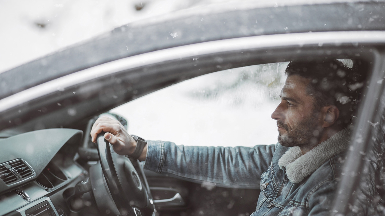 Focused driver looks at the road driving in snowy conditions