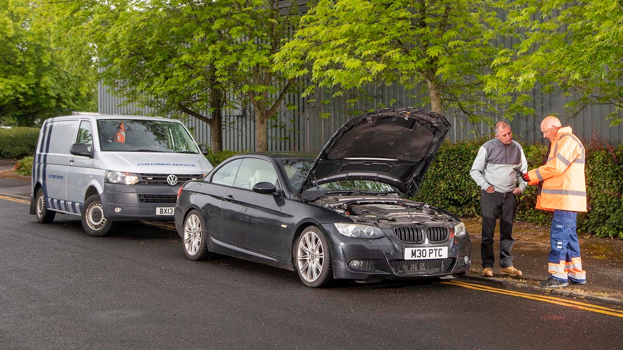 Broken-down car with recovery van behind it – driver and engineer are talking off to one side