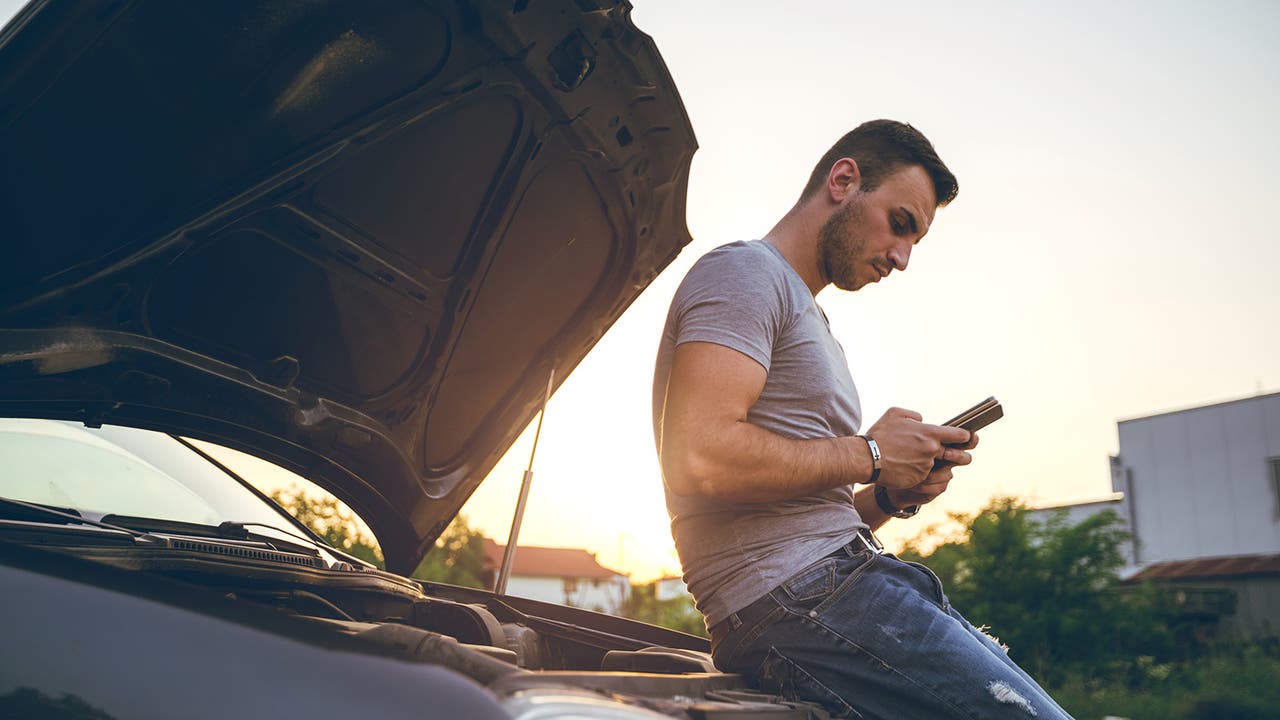 Man on phone by car with bonnet open