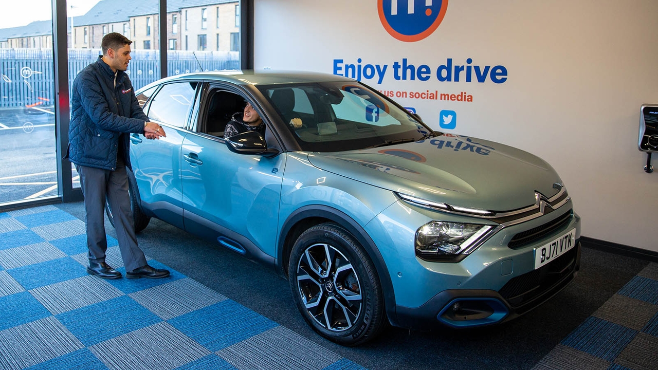 Motorpoint staff member hands over a light blue Citroen C4 to a customer