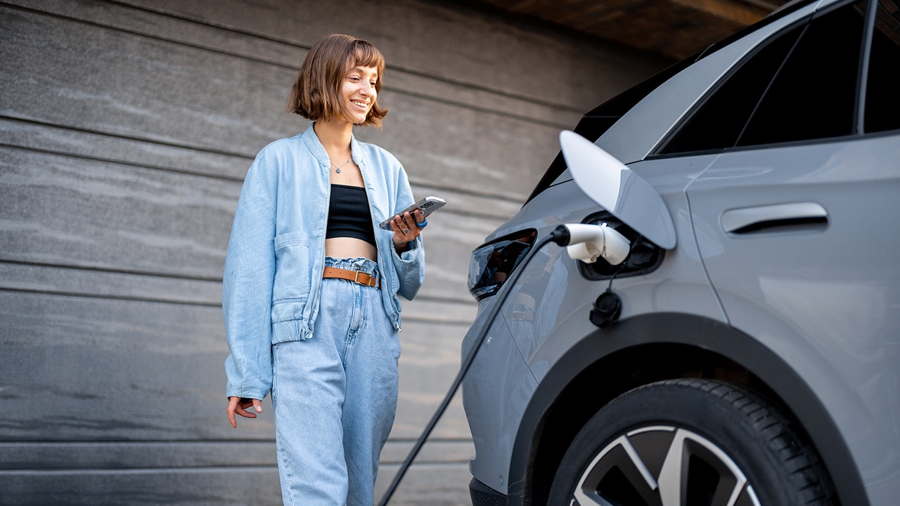 Person charging EV at home with phone