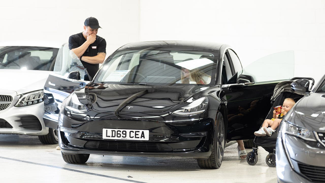 Family inspecting a black Tesla Model 3