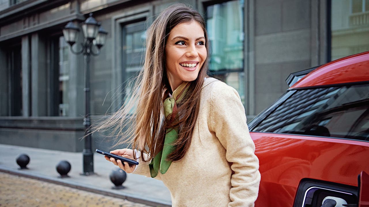 Smiling woman next to a charging EV