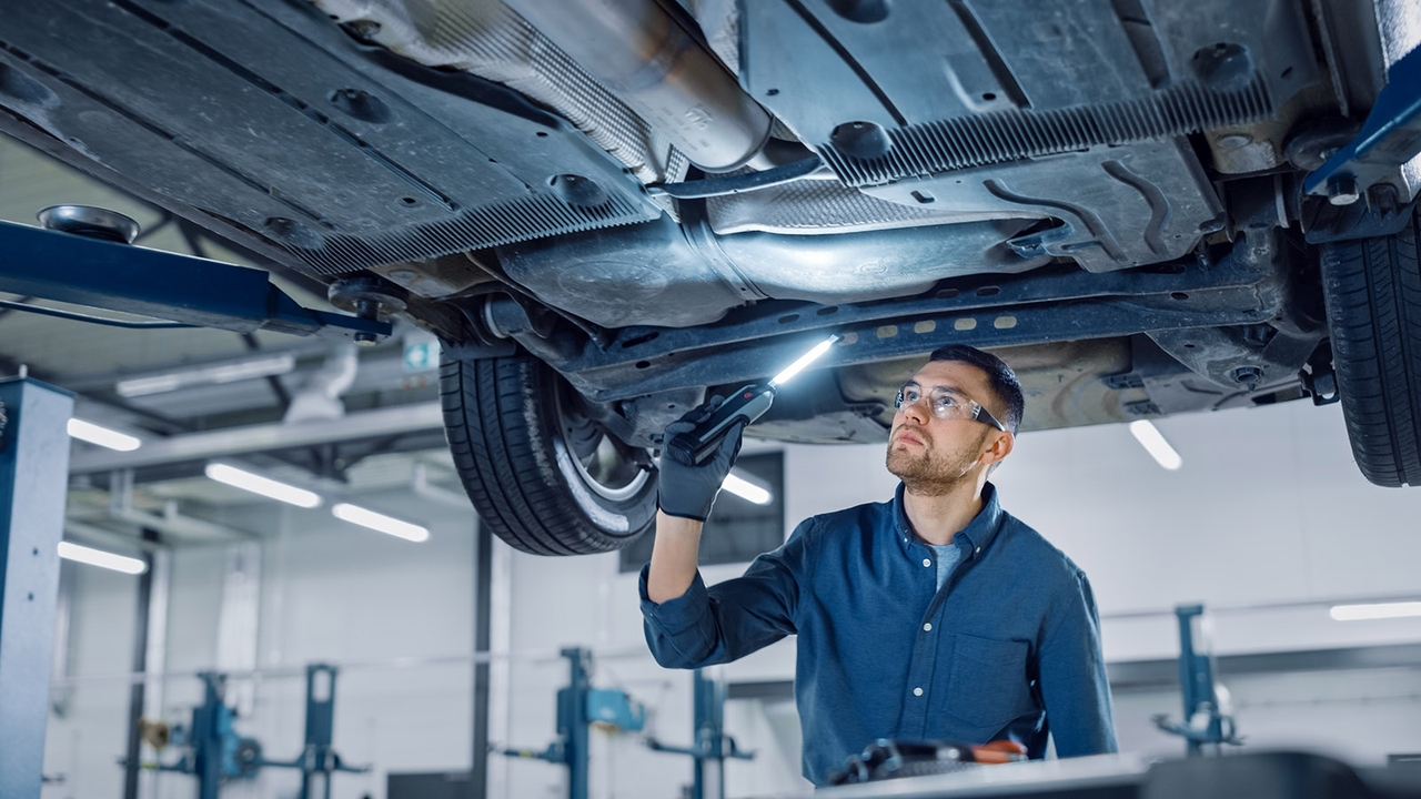 Person inspects underside of car