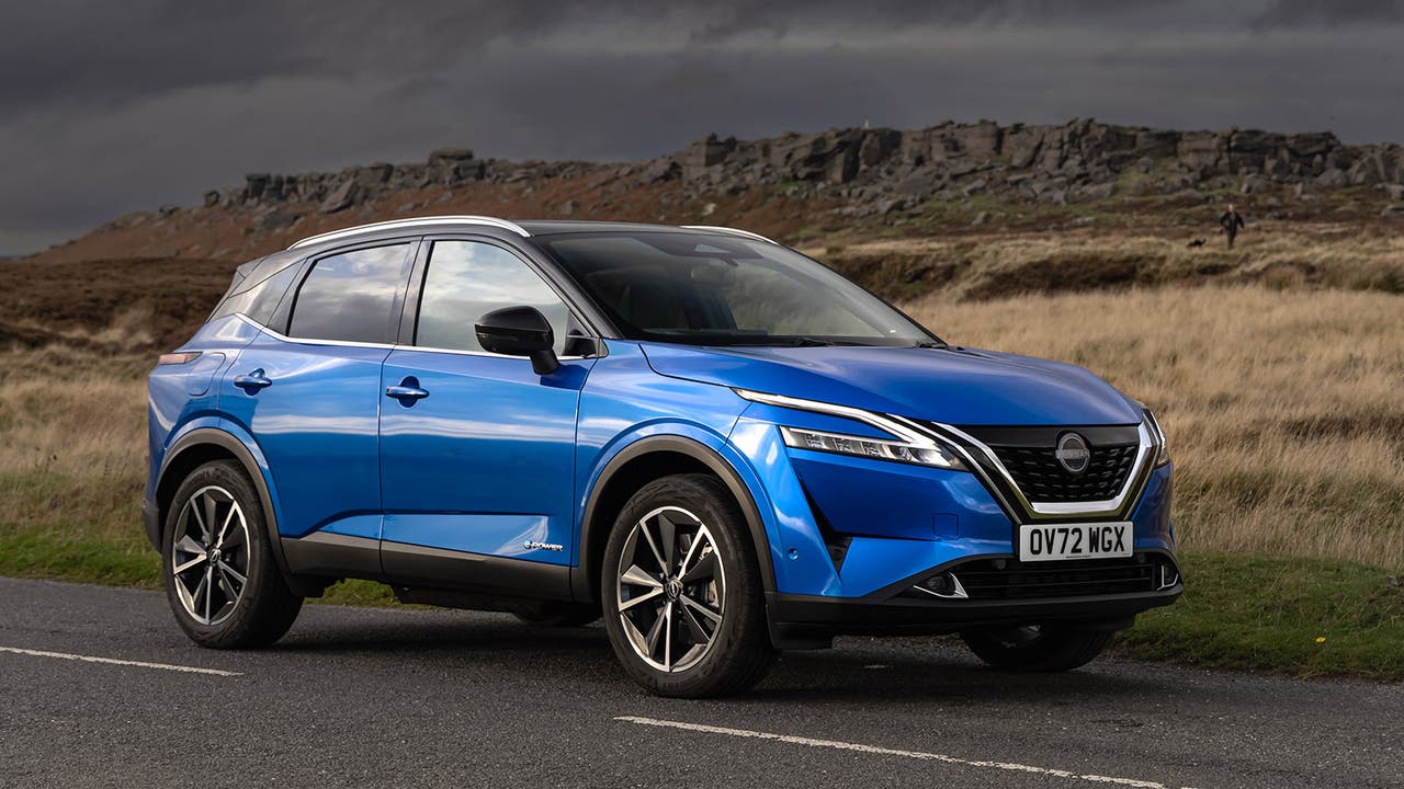 Blue Nissan Qashqai parked on a country road with a stormy sky in the background
