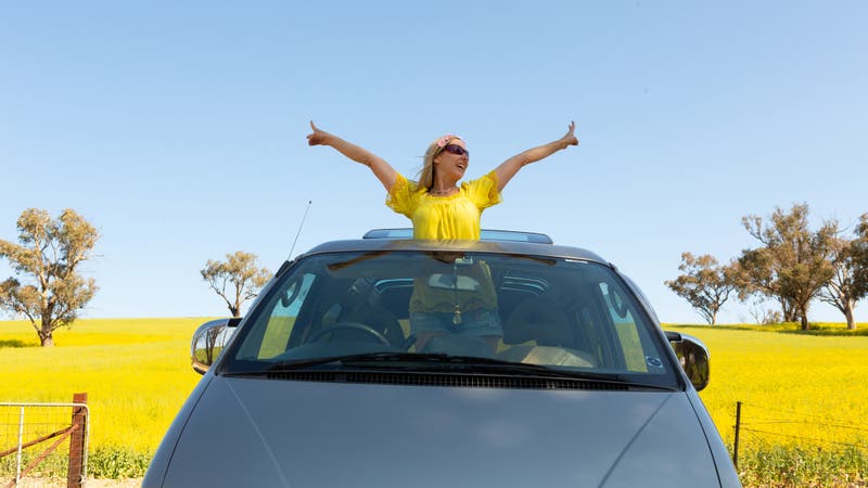 Happy woman standing in car with sunroof