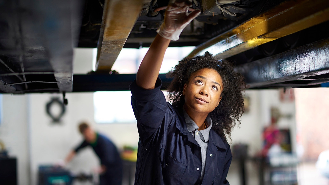 Person inspecting underside of car