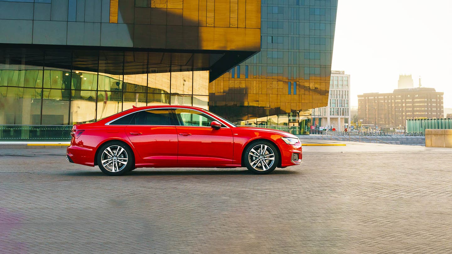 Red Audi A6 saloon car parked in front of city building