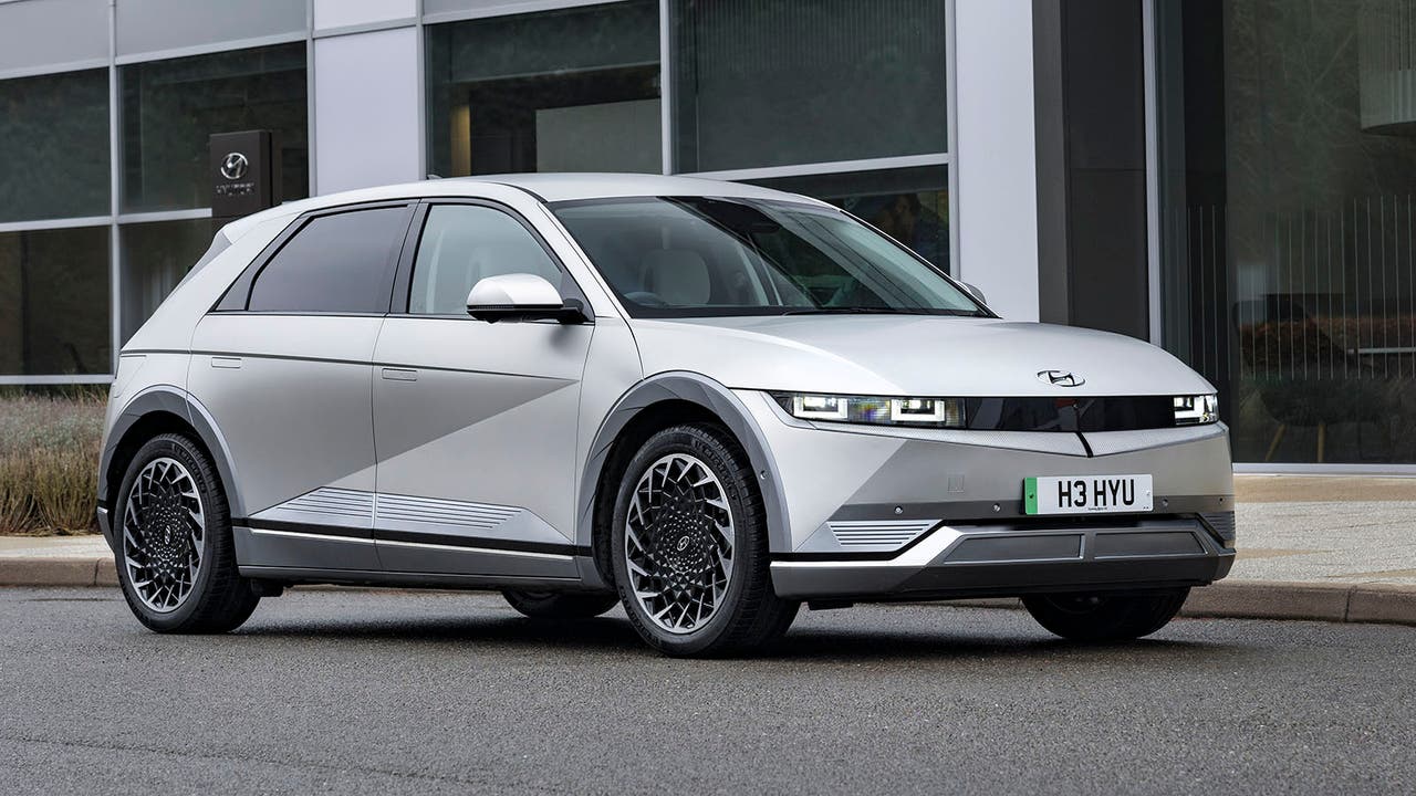 A silver Hyundai Ioniq 5 parked against a corporate-looking building