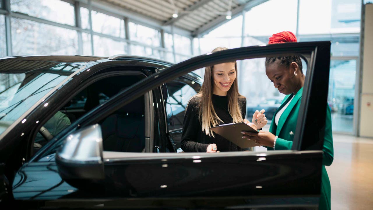 Salesperson and customer standing by car