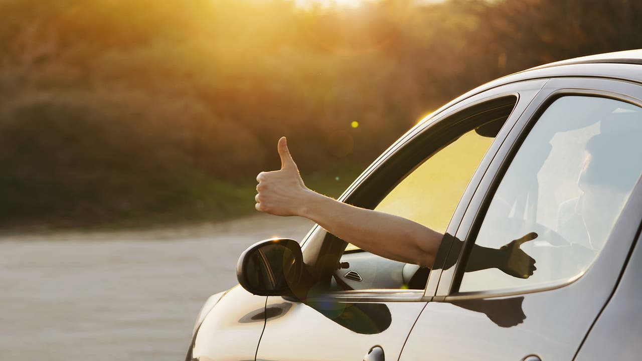 Person giving a thumbs up through an open car window