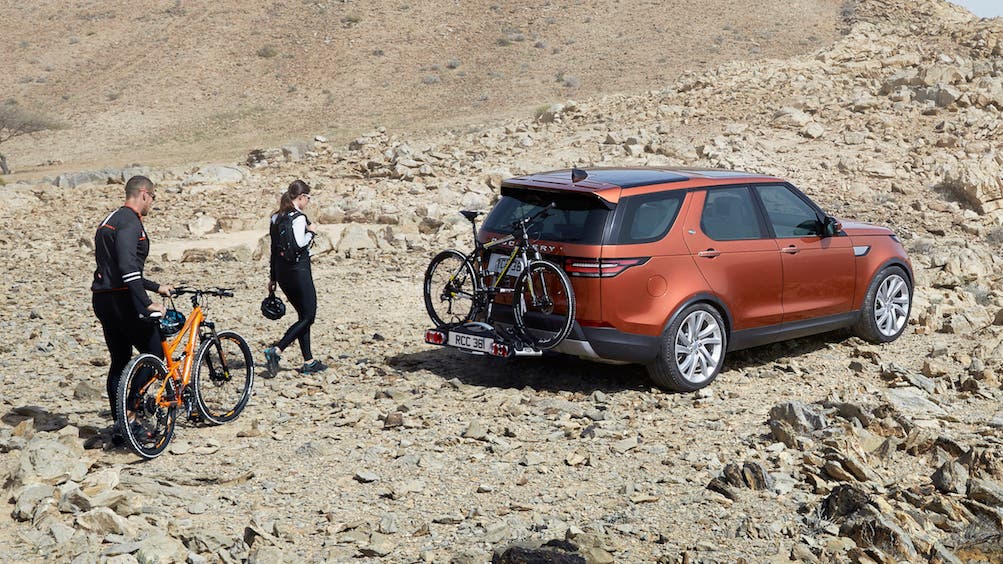 Land Rover Discovery parked on rough terrain with two people and bikes nearby
