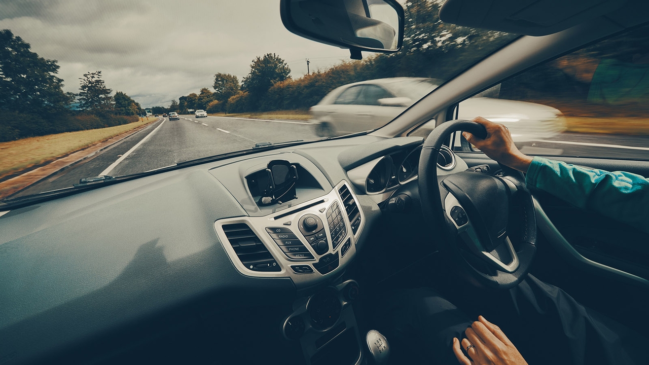 Over-shoulder shot of person driving a Ford Fiesta down a UK country road