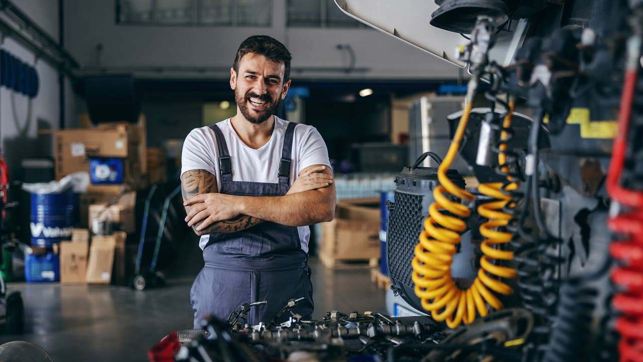Happy mechanic stands in a car service centre