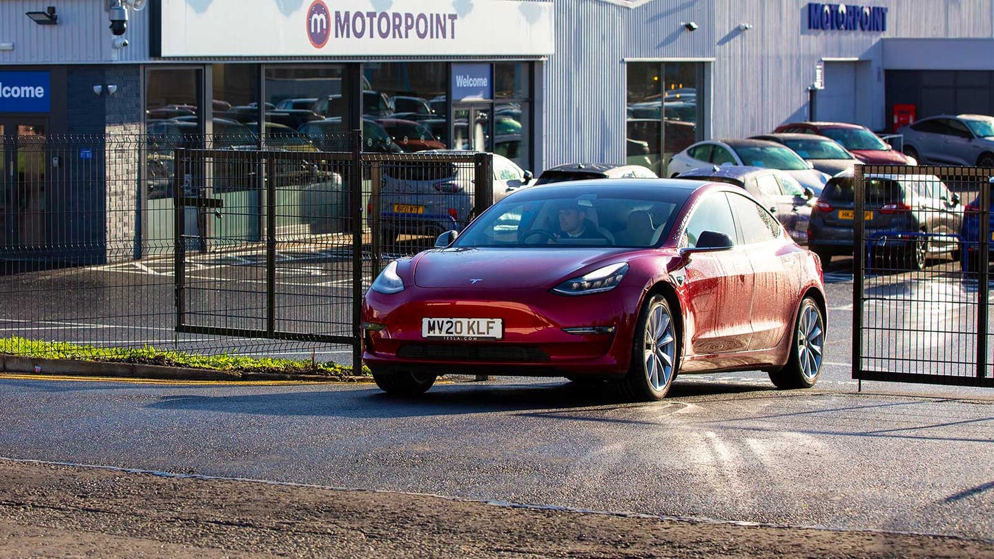 red tesla being driven out of motorpoint store