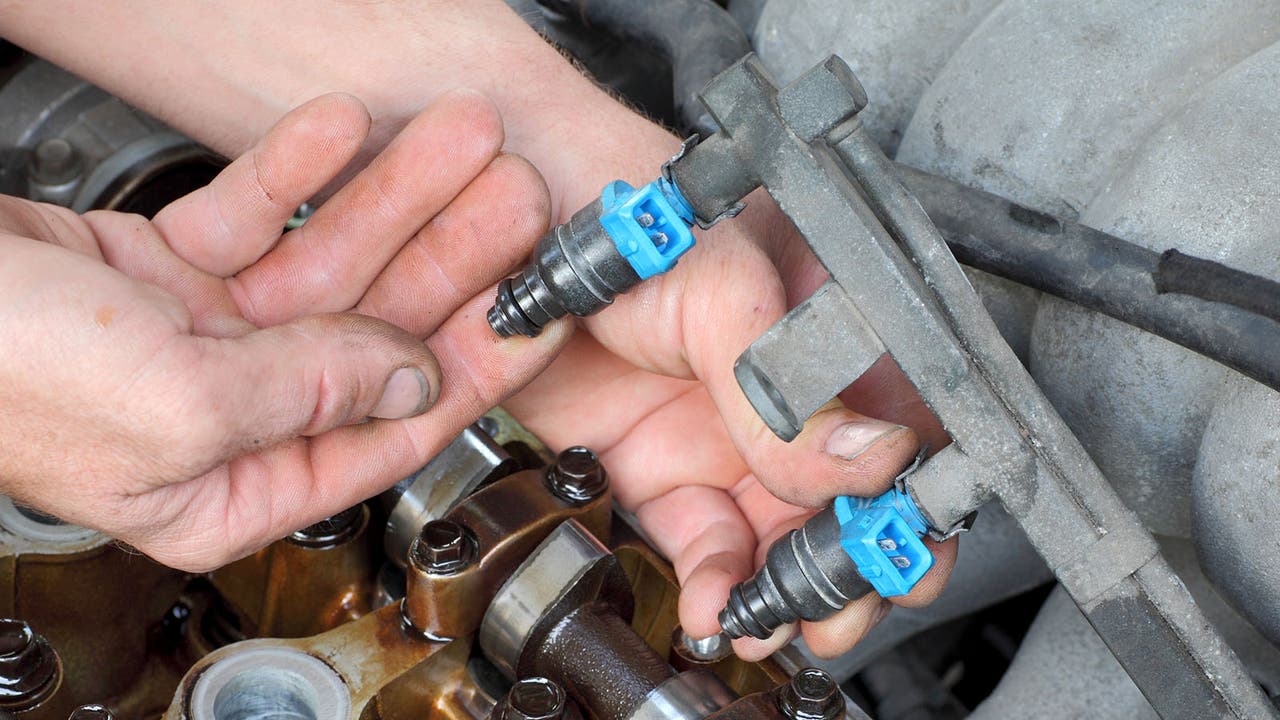 A mechanic pulls some fuel injectors out from an engine