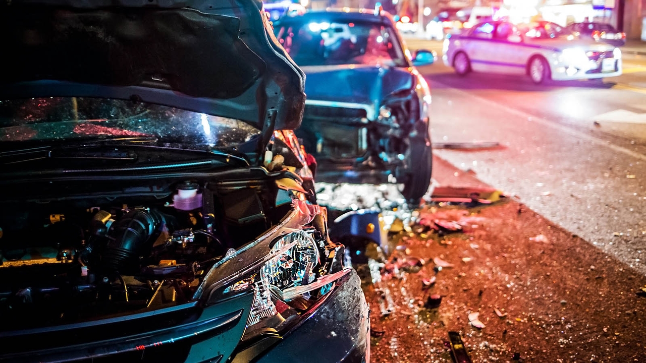 Car crash scene at night time with police car in background