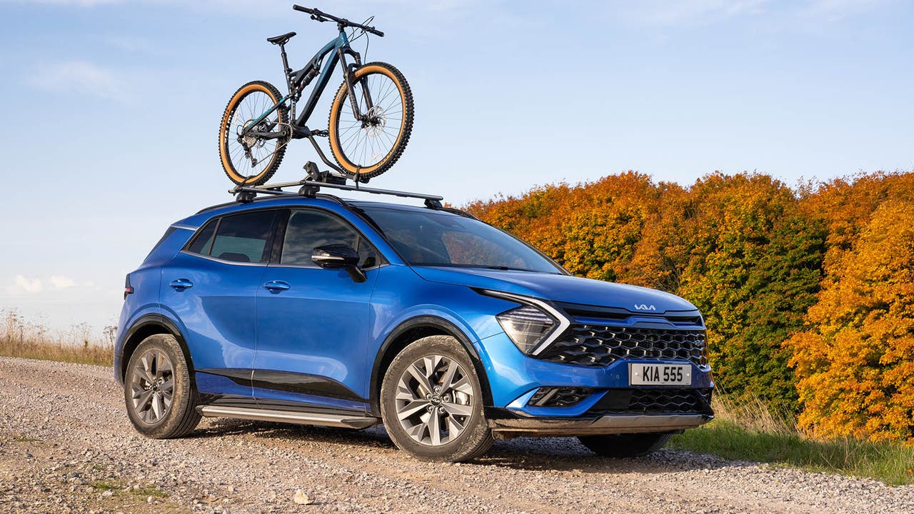 Blue Kia Sportage parked on a gravel track with a mountain bike on its roof