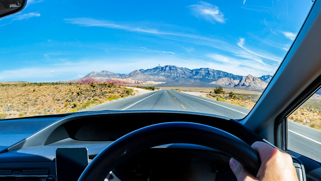 Driver's point-of-view shot looking over the steering wheel at a long open road