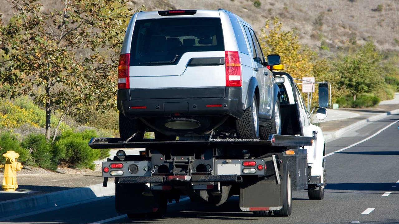 A silver Land Rover Discovery is carried on the back of a tow truck