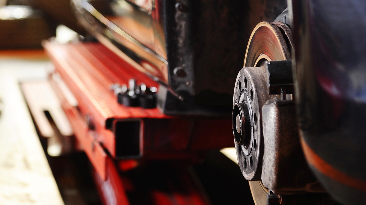 Car being serviced with a wheel removed and its brake assembly exposed