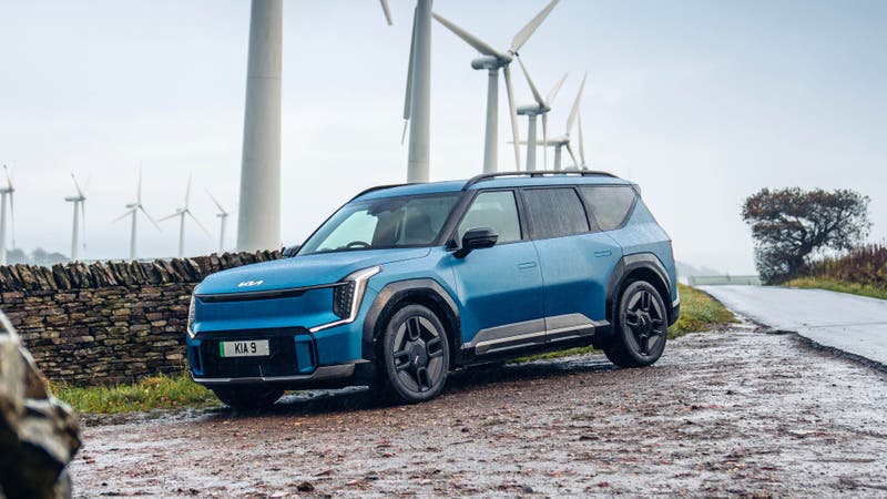 Kia EV9 parked next to wind turbines