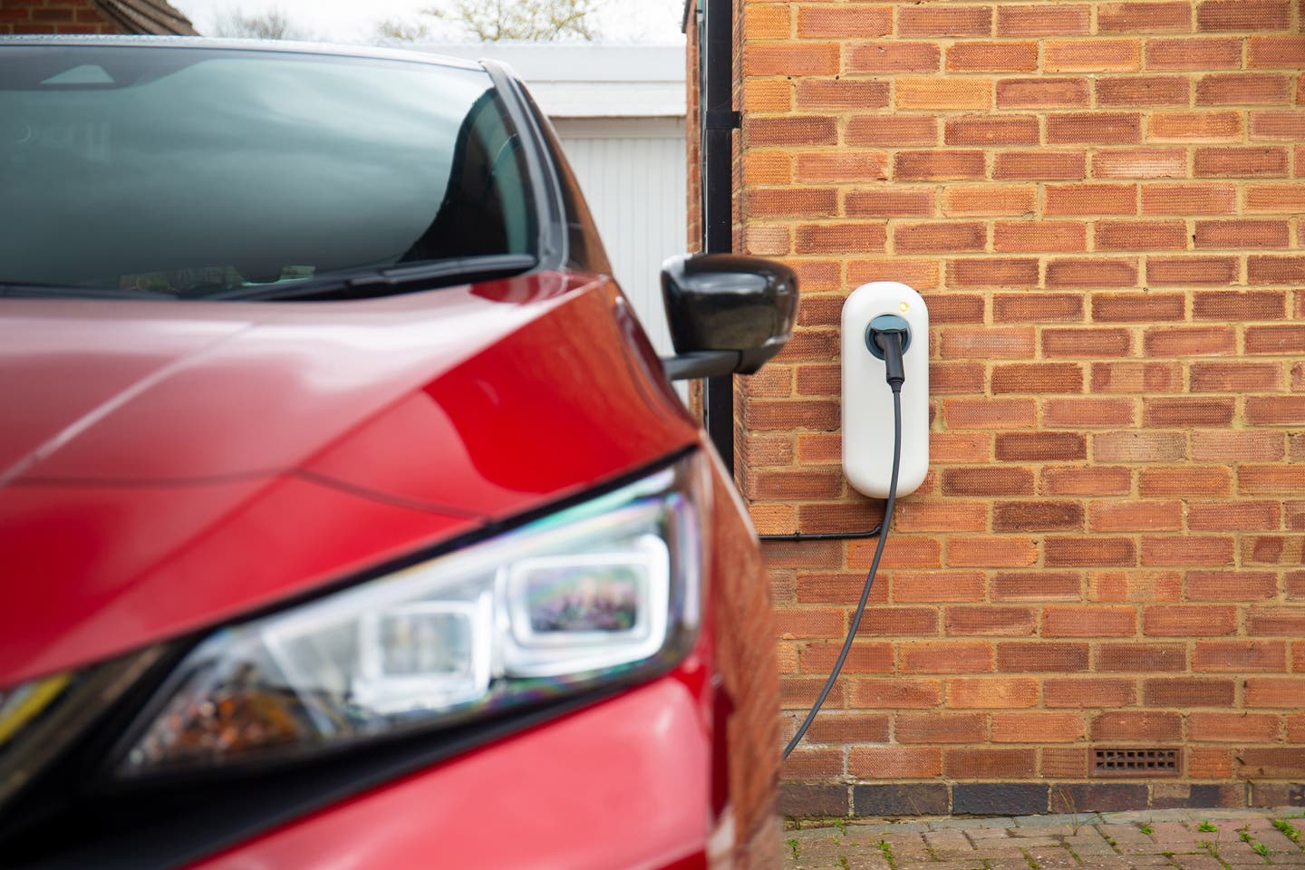 Red Nissan Leaf charging from a domestic wallbox