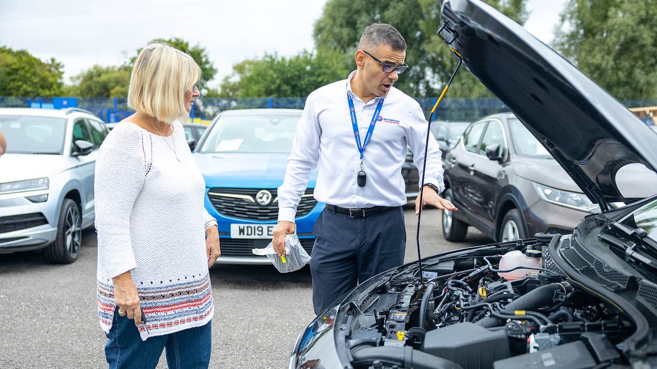 Customer and Motorpoint salesperson look at the engine bay of a car at a store