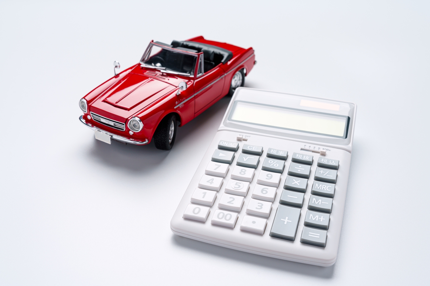 red miniature toy car next to calculator