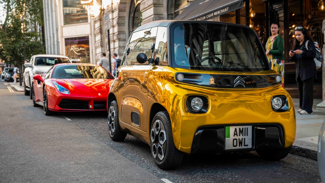 Gold-wrapped Citroen Ami in front of a Ferrari