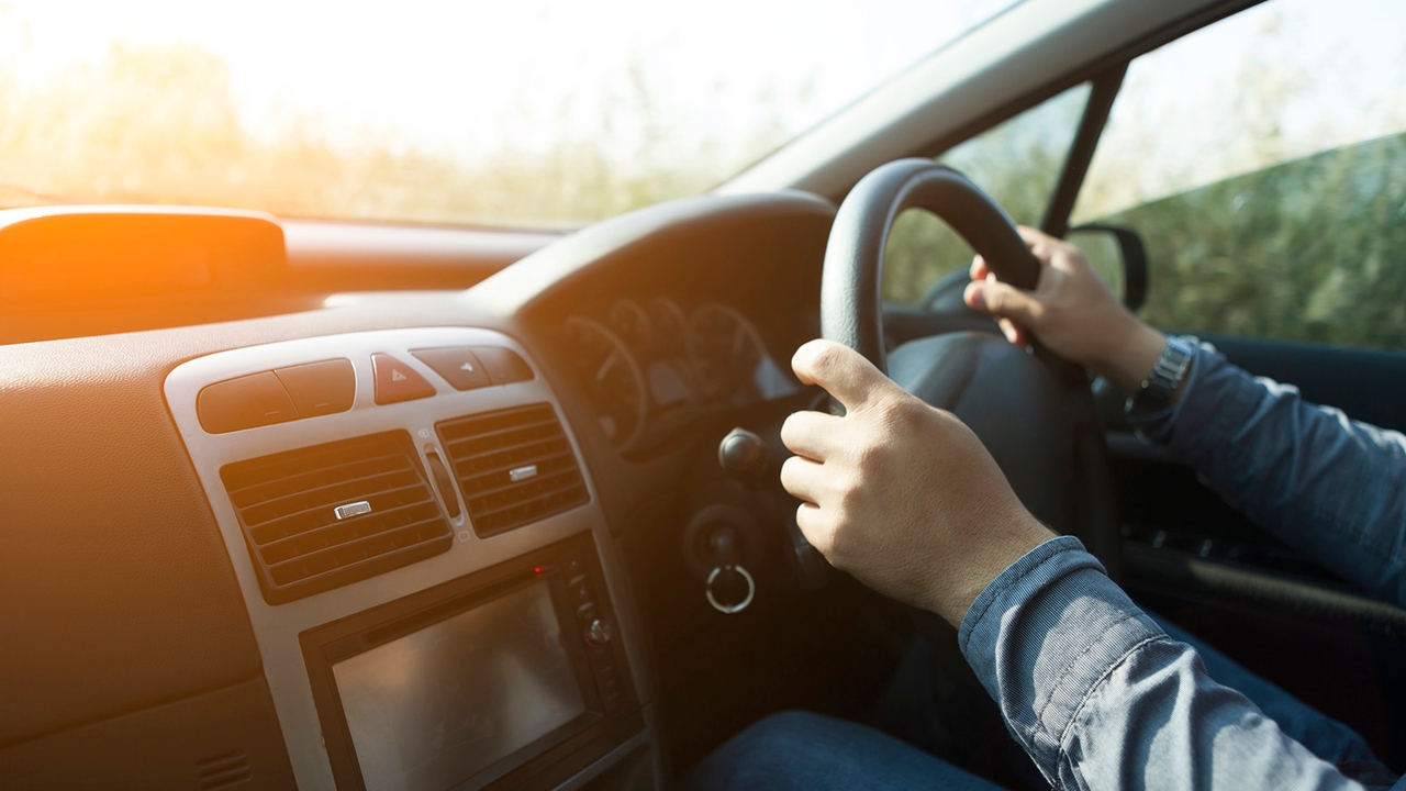 A person out of frame has their hands on the wheel while driving a car