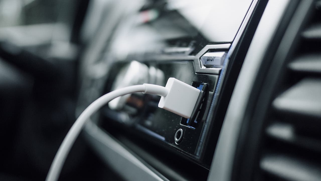 An aftermarket car head unit with a USB cable stuck into it