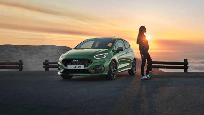 Ford Fiesta ST in green static shot, driver stands next to car facing away as if contemplating what alternative cars they might've bought