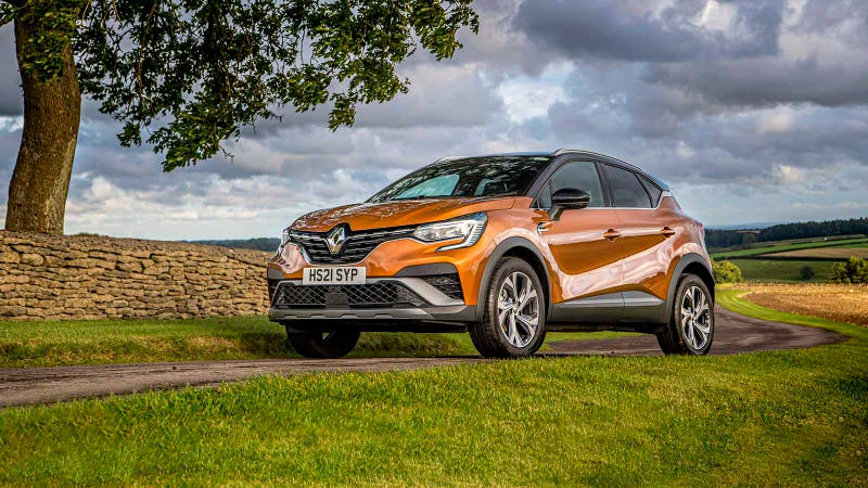 Renault Captur in orange, static shot, in a grassy field beneath a mighty oak or similarly large tree