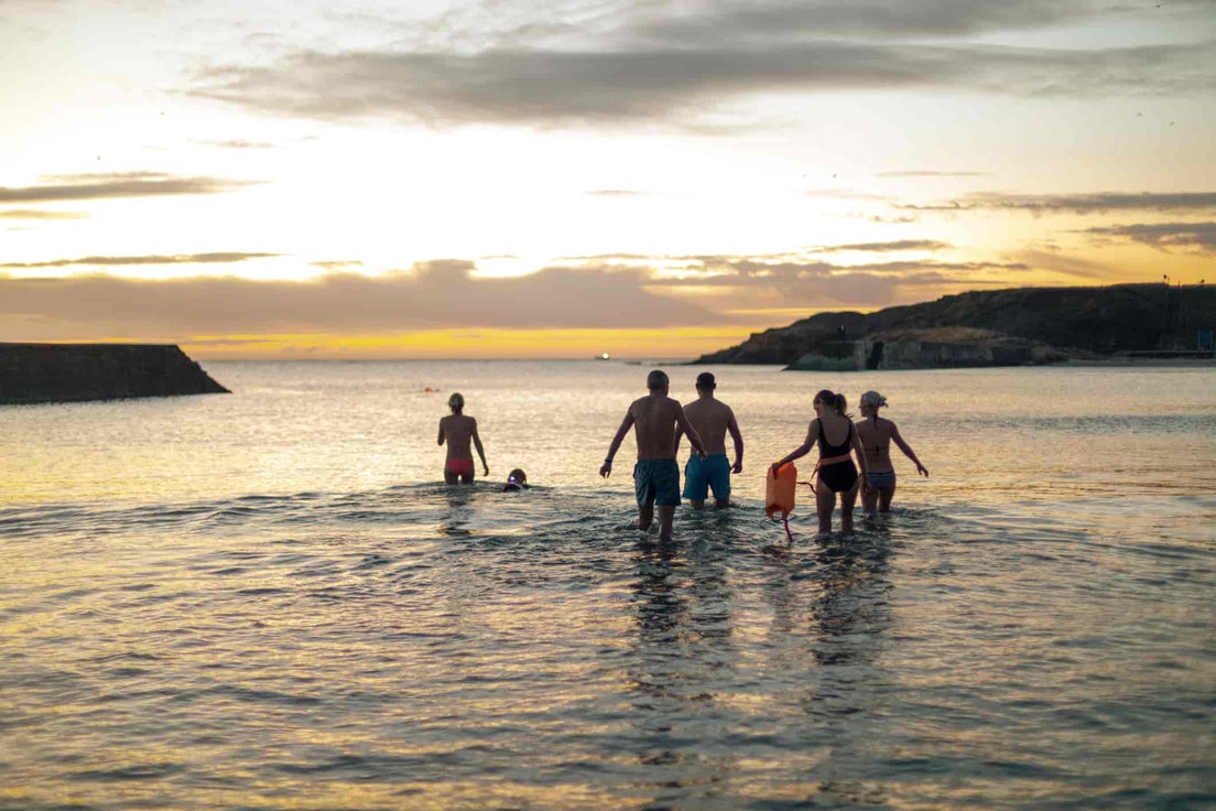 A family running into the sea at sun set.