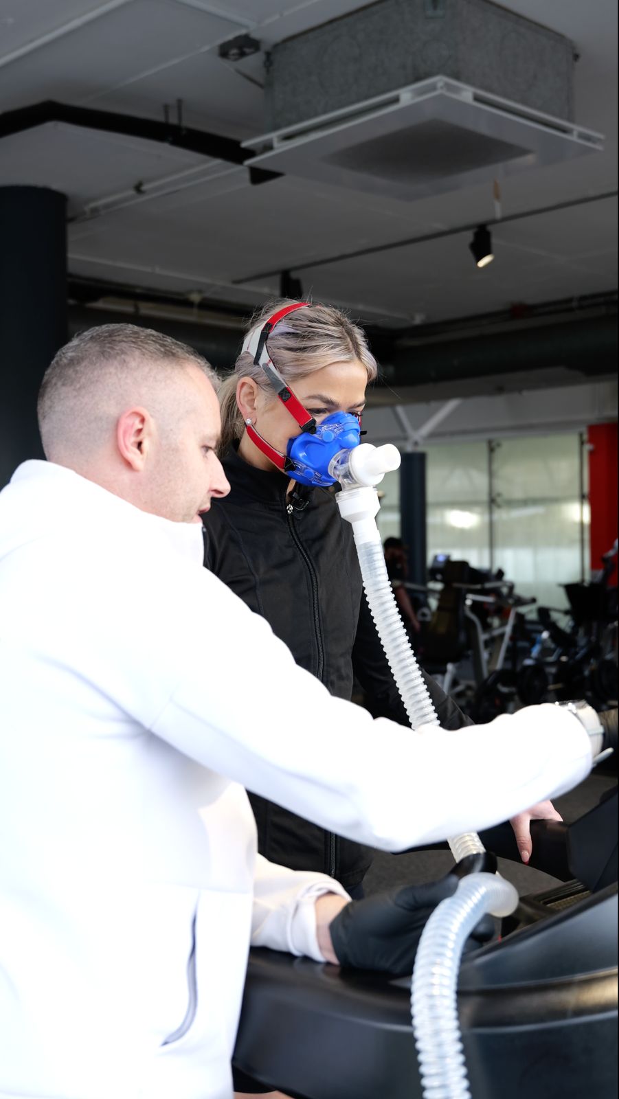 A woman breathes into an oxygen measurement device. In front of her is a laptop with diagnostic information on her metabolic rate.