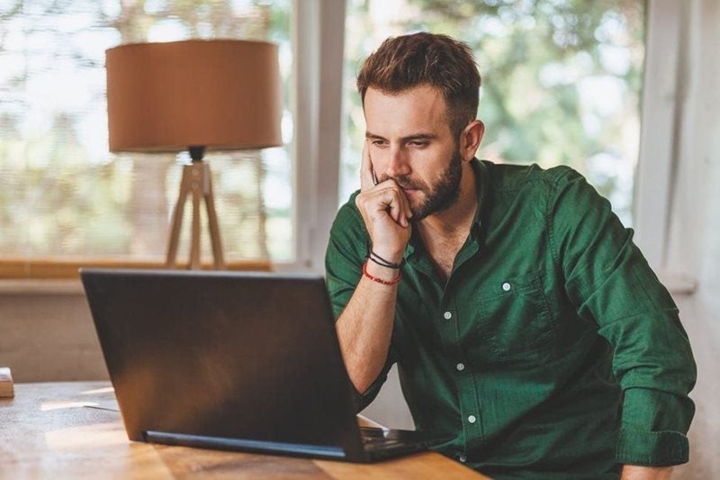A man thinking while looking at a laptop.