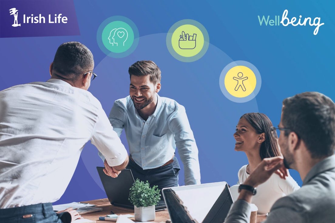 employees around a table smiling and shaking hands
